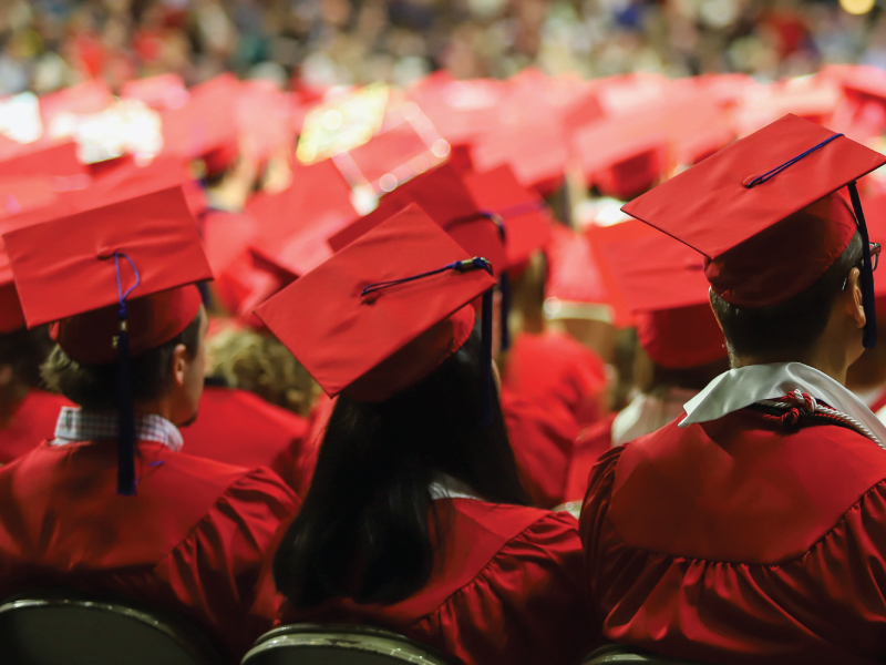 Students sitting in their cap and gowns at graduation.