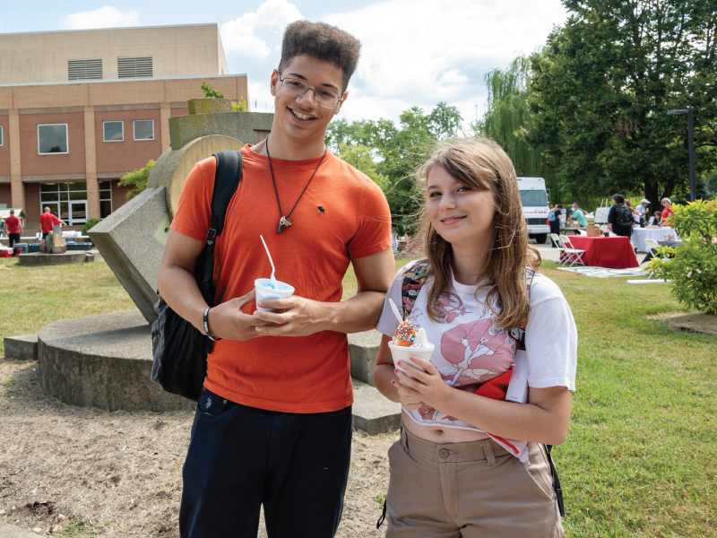 A male and female student with ice cream during fall fest at the Hamilton campus.