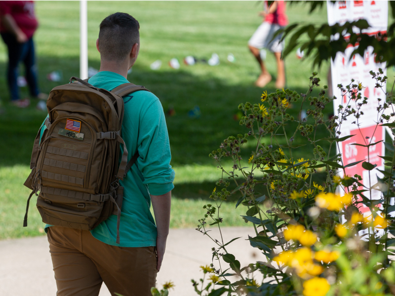 A student walking outside with a backpack with an American flag.