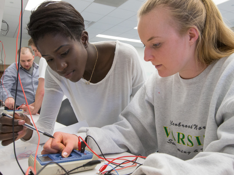 Two students working on a project involving wires and electronics