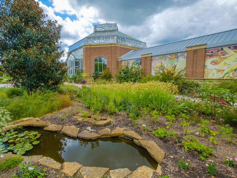 Exterior of The Conservatory with view of formal plantings and water feature.