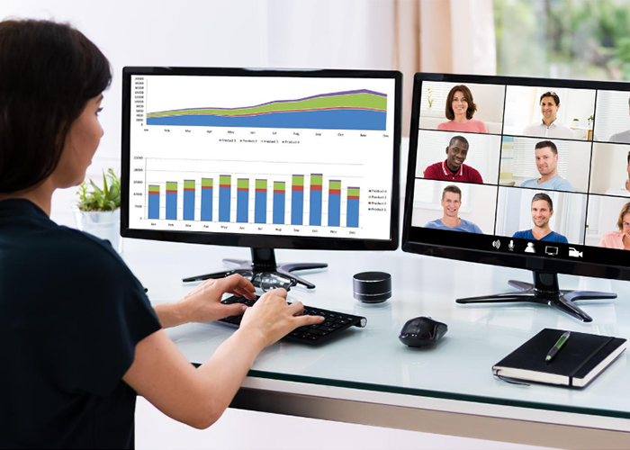 Woman in a video conference with participants and charts on different monitors
