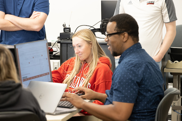 A student and an advisor work together on a computer.