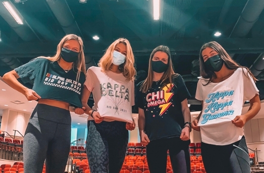 4 female masked students wearing sorority chapter shirts in an empty Wilks Theater