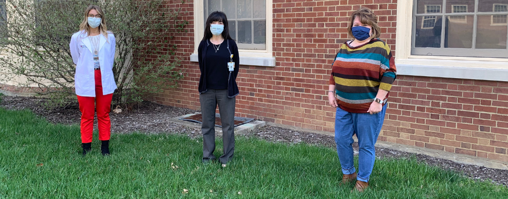 Becky Stephenson, Karla McClain, and Beth Tonyan wearing masks and standing distanced apart at the side of Harris Hall.