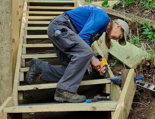 Nancy Feakes works on a set of wooden steps on a steep trail