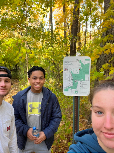 Three students standing next to a map of the natural areas.