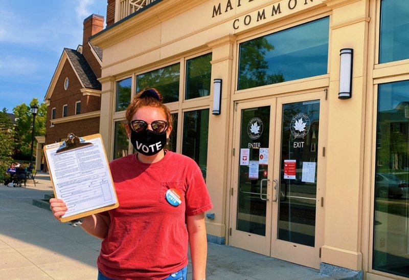 Student Reena Murphy holding up voter registration forms outside Maplestreet Commons