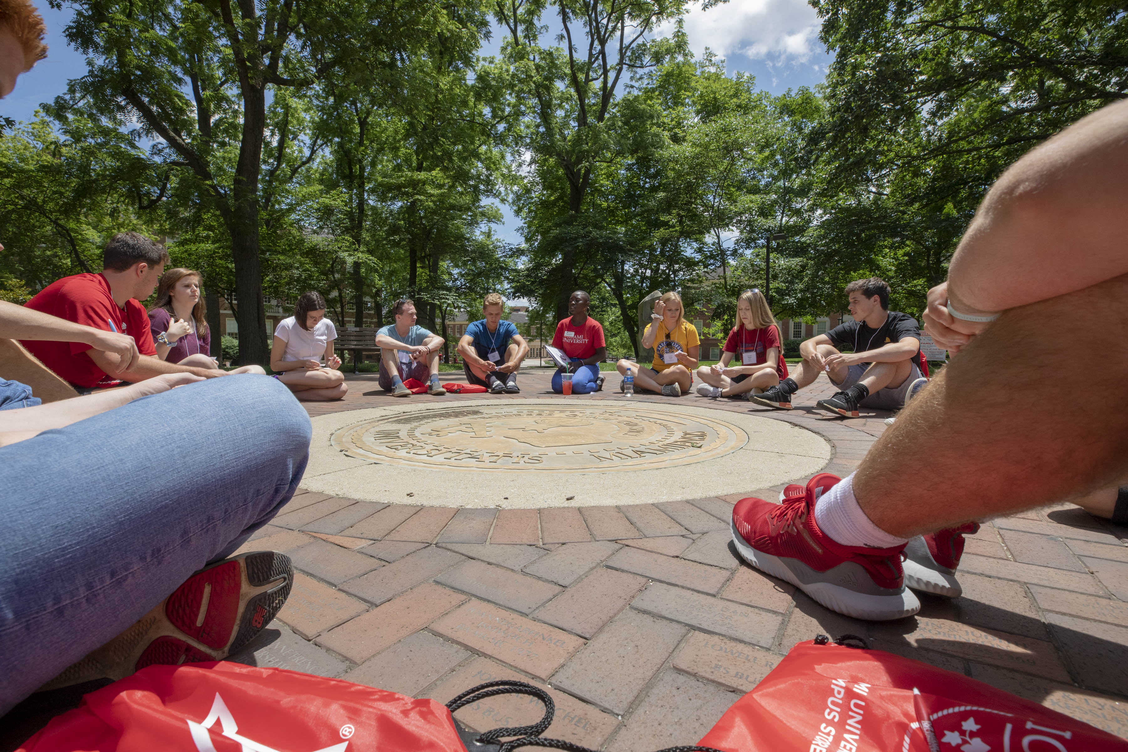 Group of 15 students sitting in a circle around the seal for orientation