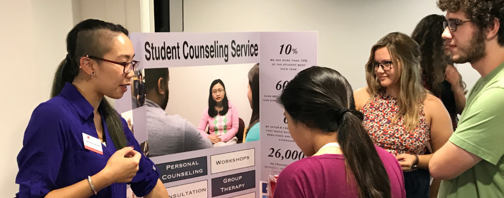  Psychologist from the counseling center talking to students at an information table. 