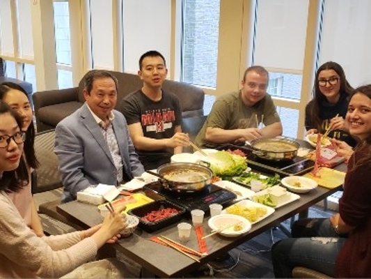  7 people seated at a table full of food, looking at the camera