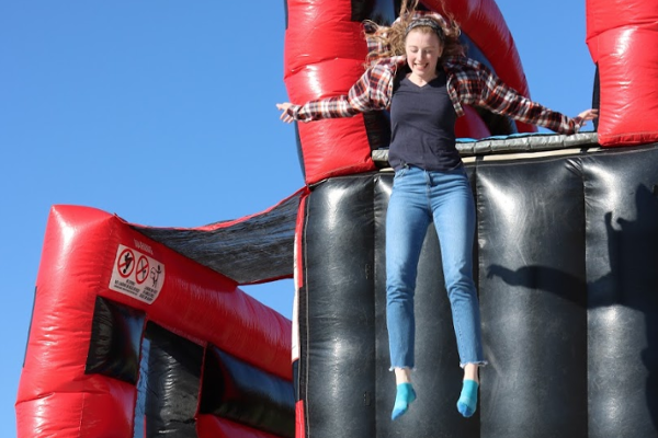 A student in mid-air jump down a huge inflatable at an outdoor MAP event