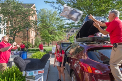 Parents and students unloading a car in front of a residence hall on Move In Day