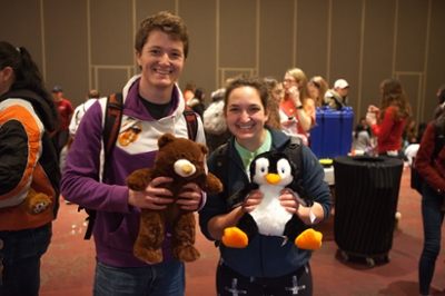 Two students holding up a stuffed bear and penguin