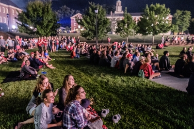 large group of students watching an outdoor movie at night