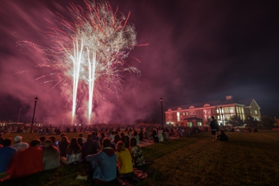 Fireworks show over Benton Hall with large group of students watching