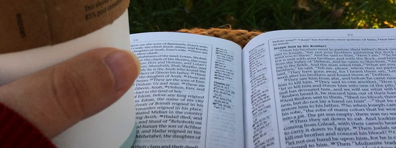  A POV shot of a person reading the Bible with a cup of coffee in hand