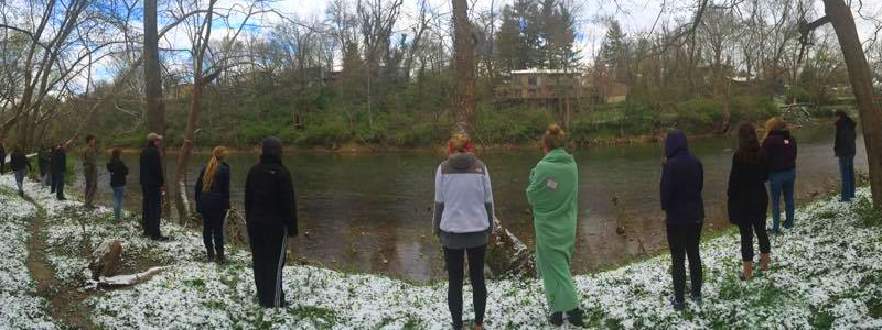  Students standing contemplatively on a riverbank