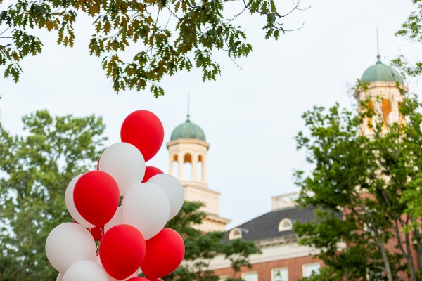 Red and white balloons floating in front of a cuppola 